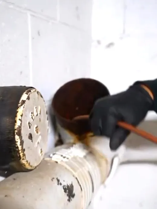 Two capped cast iron cleanouts on a horizontal waste line, one opened