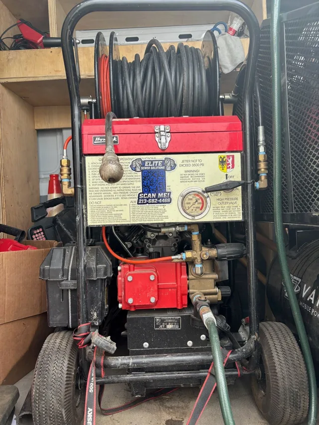 The company’s own wheeled hydro jetter loaded in the van, hose reel above the pump and the pressure gauge on its plate