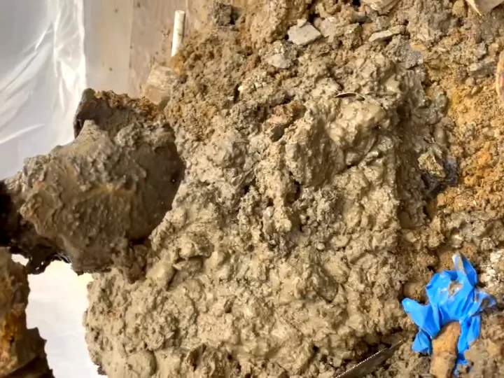 An opened floor showing collapsed ground around a failed cast iron drain line